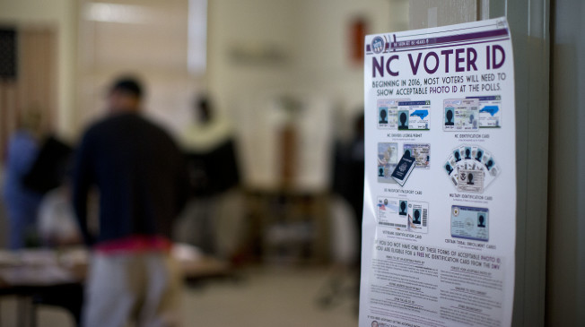 NC Voter ID rules are posted at the door of the voting station at the Alamance Fire Station, Tuesday, March 15, 2016, in Greensboro, N.C. The state's new voter identification law requires that voters show a photo identification before getting their ballot. Voters in North Carolina, as well as Missouri, Illinois, Ohio and Florida are casting their ballots in primary elections Tuesday. (Andrew Krech/News & Record via AP) MANDATORY CREDIT